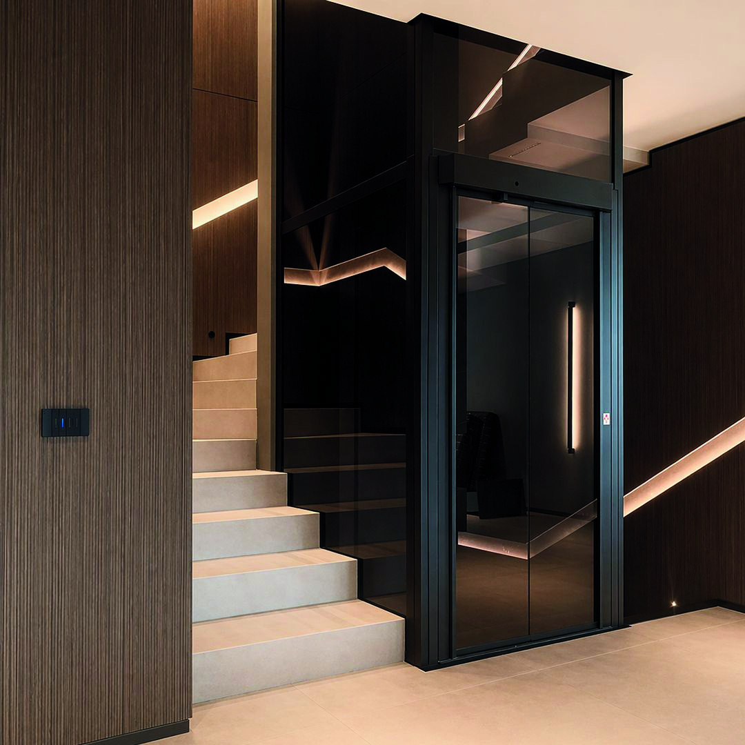 Huislift geïntegreerd naast een houten trap en wandbekleding